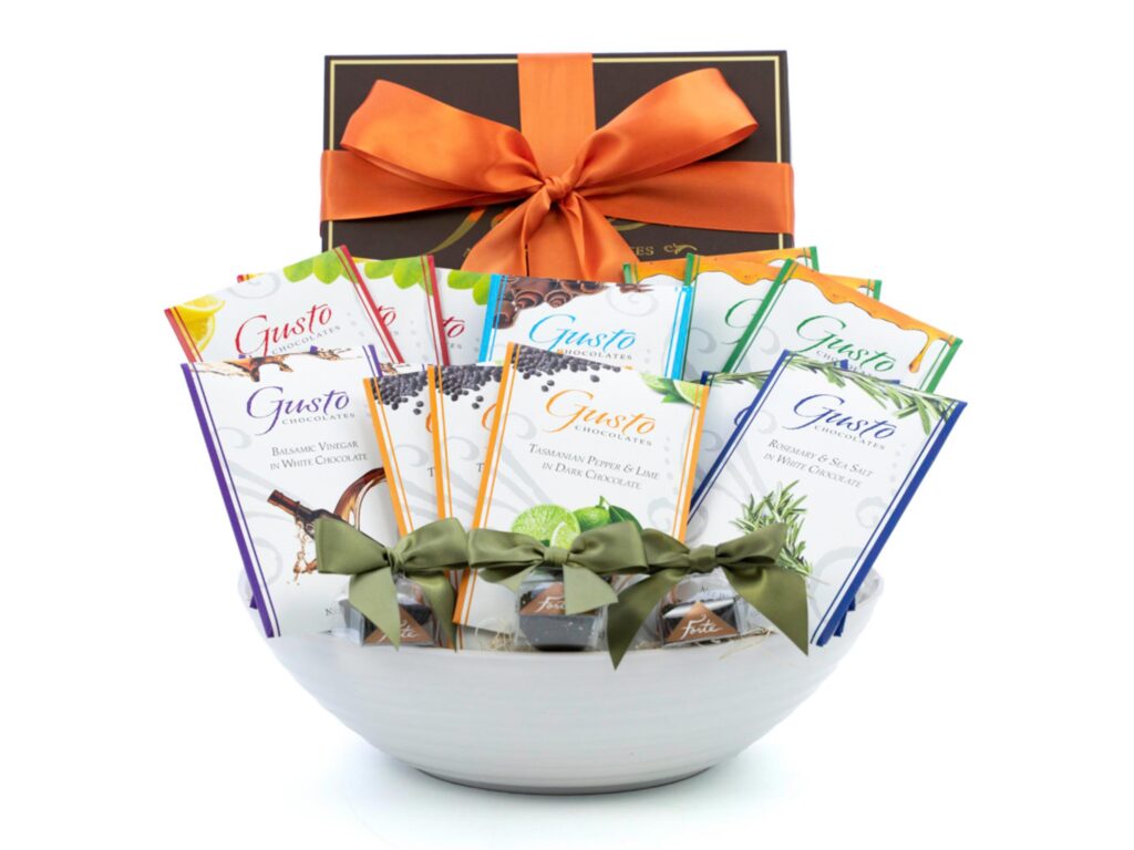 White bowl filled with green be-ribboned small totes, 13 bars and large brown box with orange ribbon