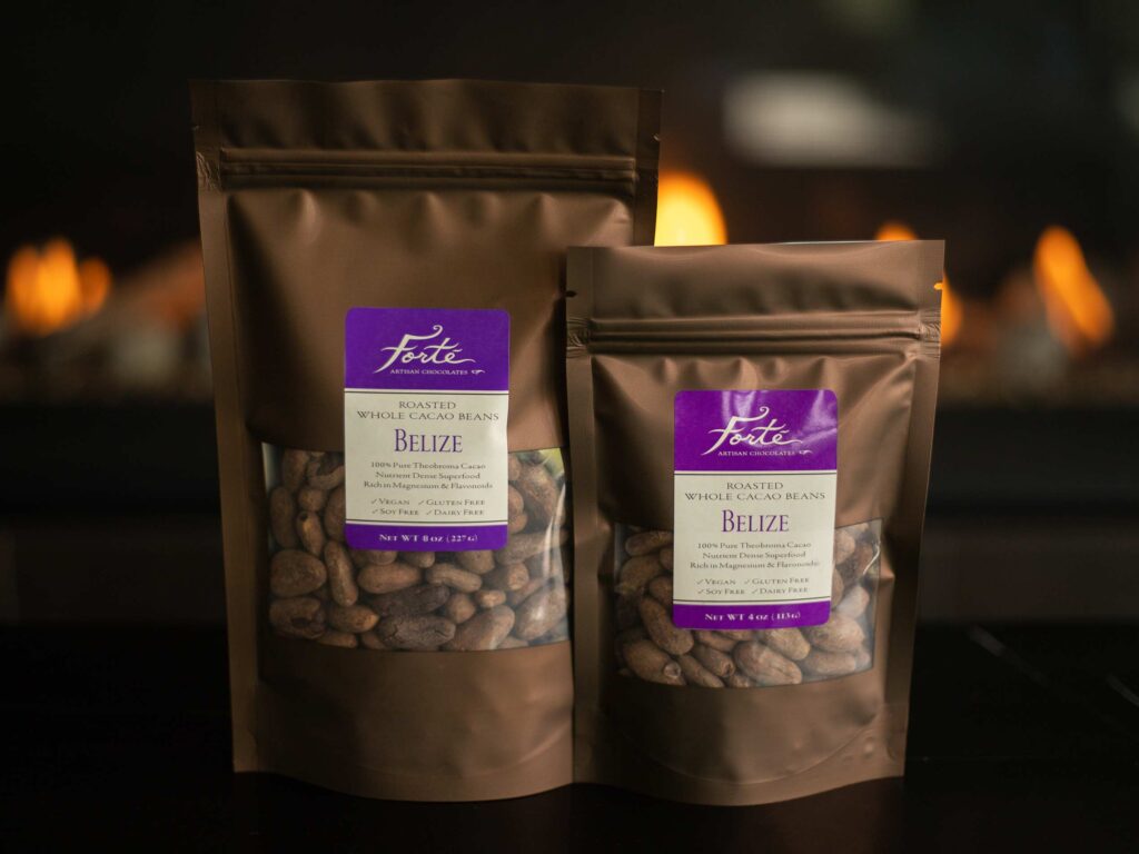 Two brown bags of differing sizes with purple labels of roasted whole cacao beans from Belize with flames in the background
