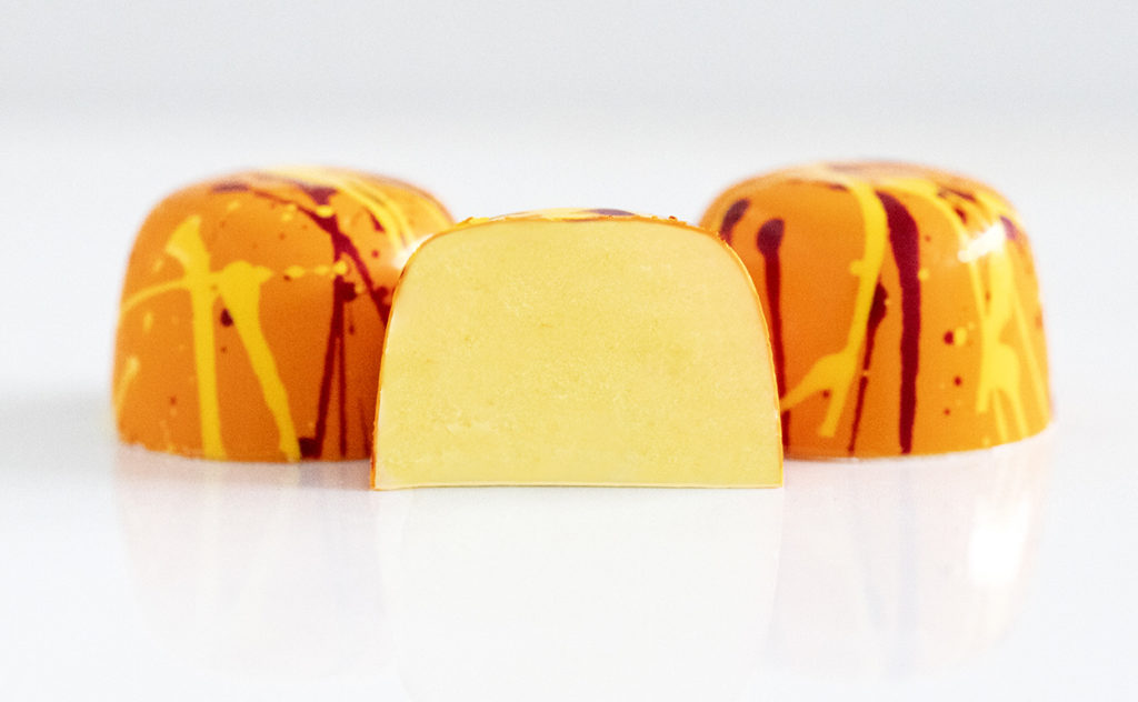 3 passion fruit truffles in bright orange with red and yellow splatters