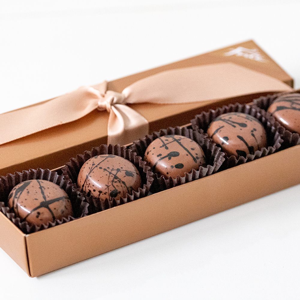 5 piece box of gourmet Espresso Truffles on marble coasters. This award-winning, reimagined classic truffle features superb local espresso beans from Olympia Coffee steeped in cream for our luscious ganache.