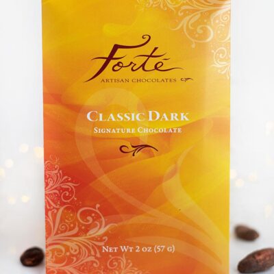 Classic dark chocolate bar packaging on white setting with cacao beans on surface