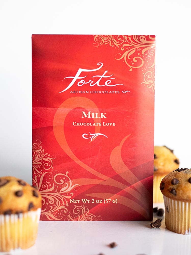Forte Milk Chocolate Love bar red packaging with gold swirls standing among 3 chocolate chip muffins