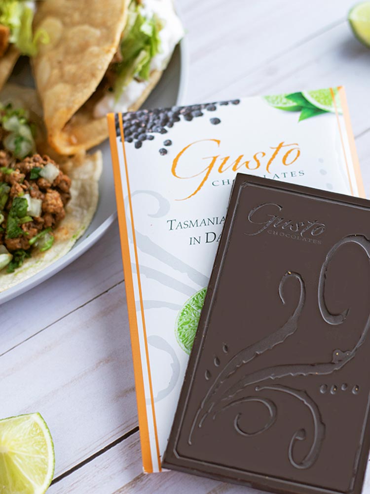 Gusto Tasmanian Pepper Lime bar sitting on top of packaging with tacos and cut limes in background