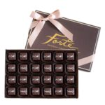 24 pieces of sea salt dark caramels in an open box with lid behind including a satin pink ribbon tied in a bow
