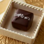 Single sea salt dark chocolate caramel in a jewel box on a gold background