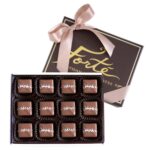 12 pieces of sea salt milk caramels in an open box with lid behind including a satin pink ribbon tied in a bow