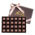 24 pieces of sea salt milk caramels in an open box with lid behind including a satin pink ribbon tied in a bow