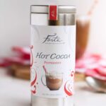Tin of Forte Peppermint hot cocoa with filled mug in background