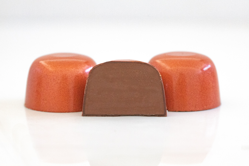 3 orange-brown classic milk chocolate truffles with middle one sliced in half showing milk chocolate ganache