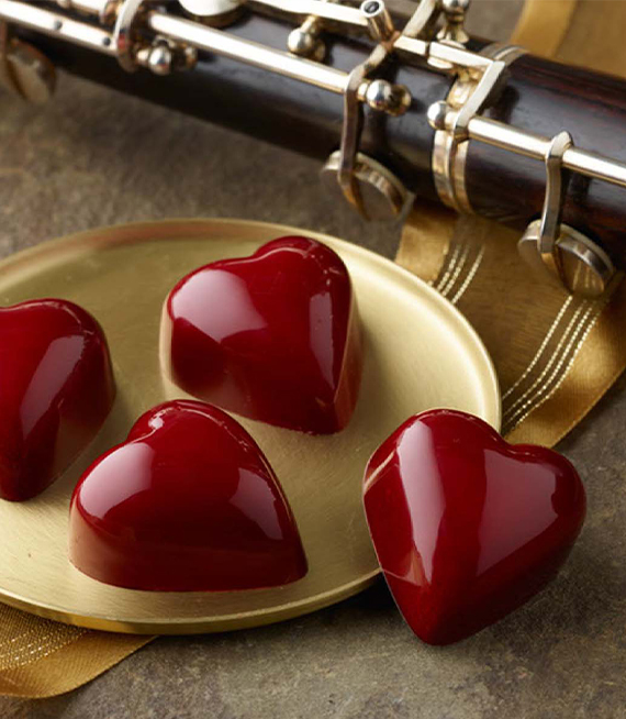 Red heart truffles on gold tray with oboe in background